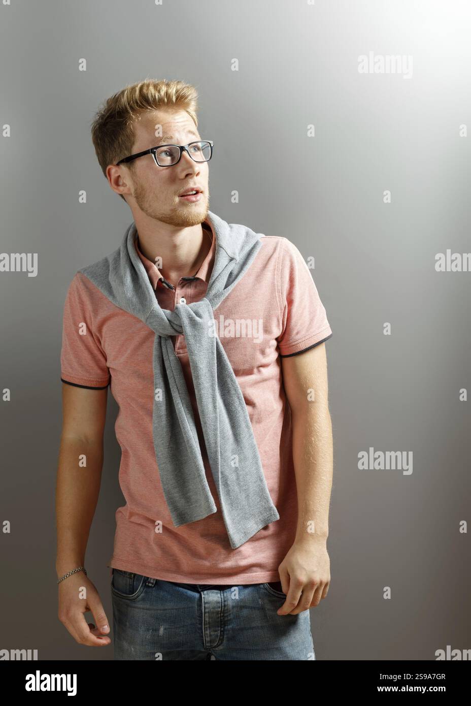 Hübscher junger blonder Mann auf grauem Hintergrund Stockfoto