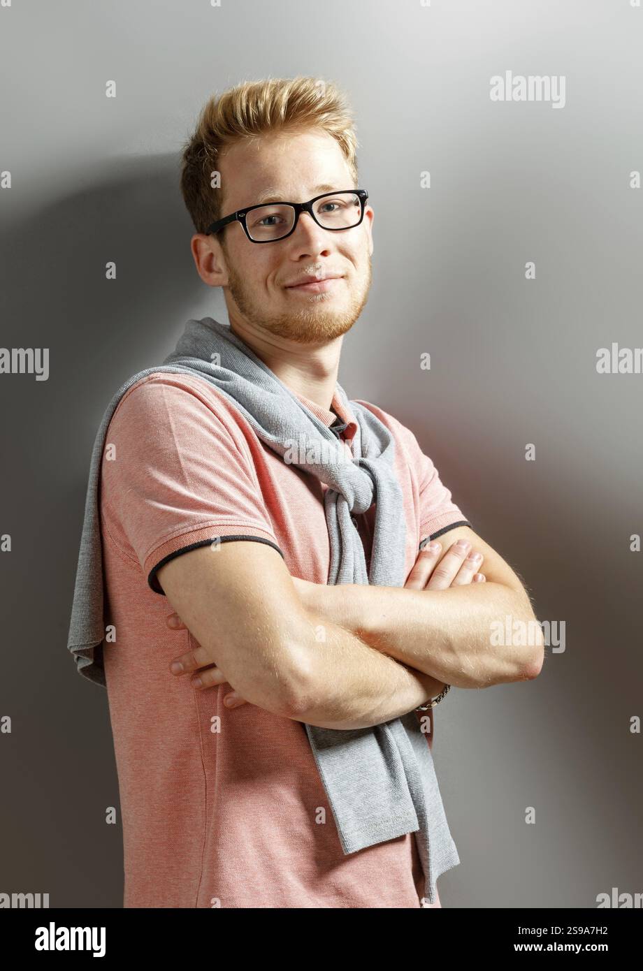 Hübscher junger blonder Mann auf grauem Hintergrund Stockfoto
