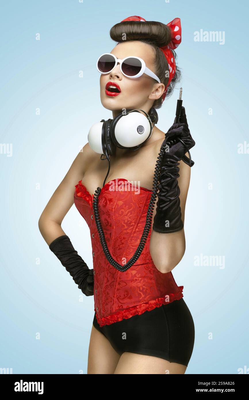 Das Pin-up-Foto eines süßen Mädchens mit Sonnenbrille und abgesteckten Kopfhörern Stockfoto