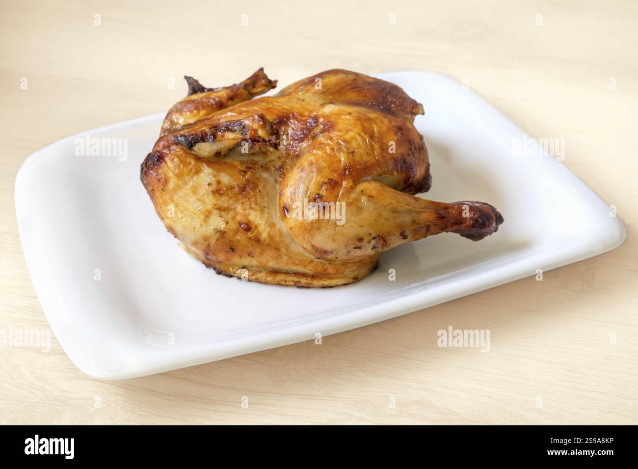Ganzes goldgeröstetes Hühnchen auf weißem Hintergrund Stockfoto