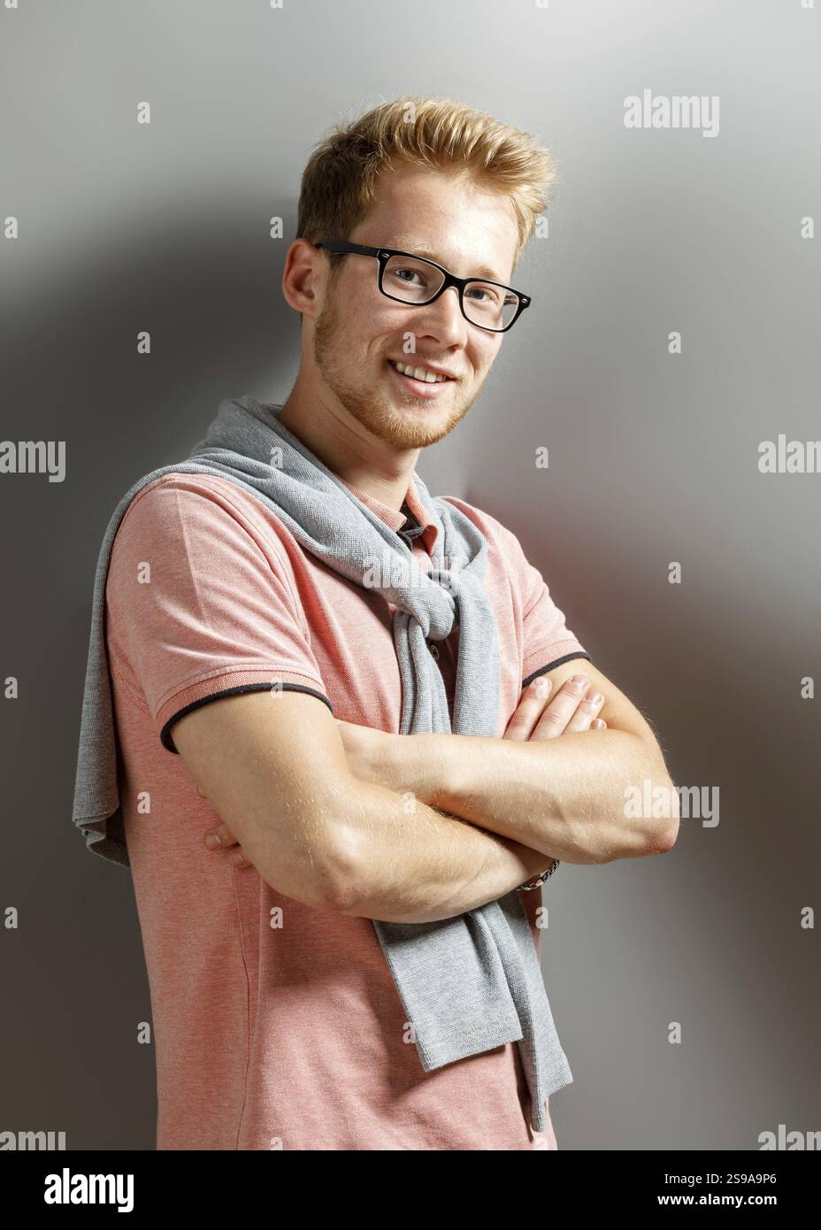 Hübscher junger blonder Mann auf grauem Hintergrund Stockfoto