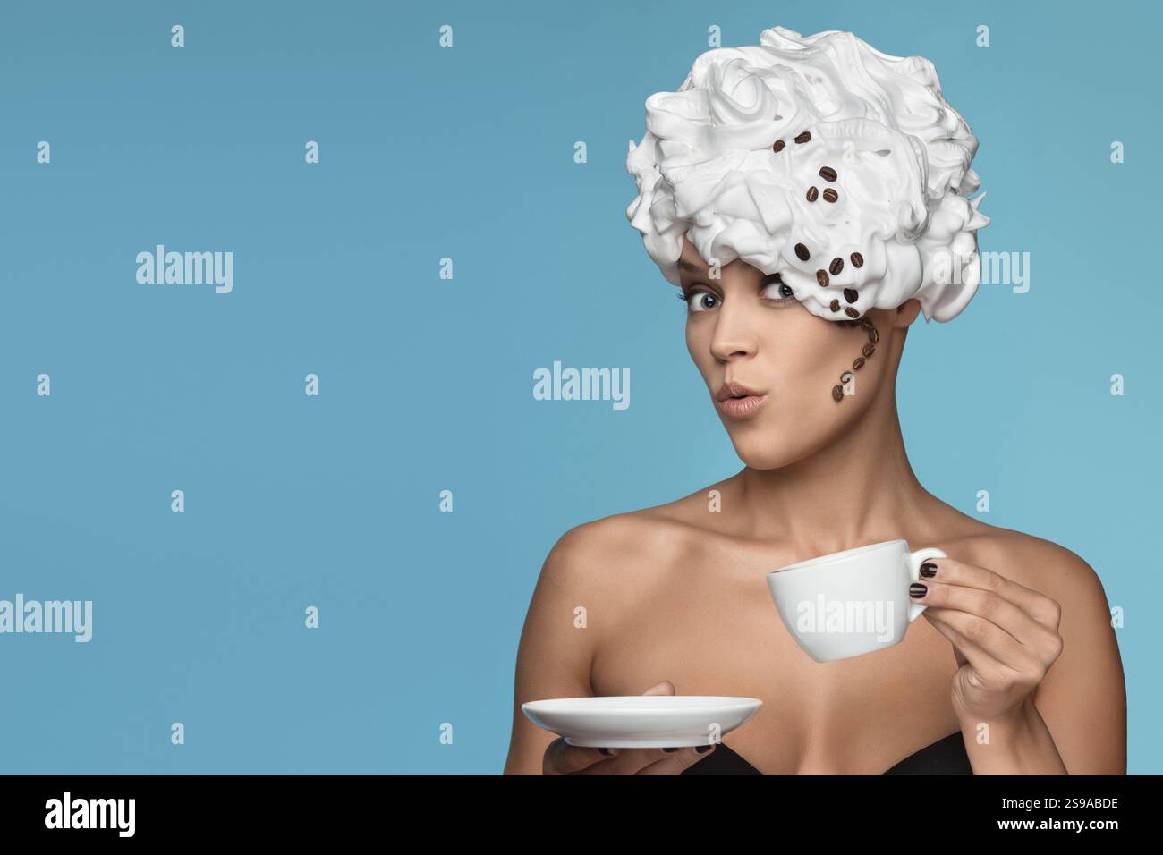 Eine junge Dame mit Schlagsahne auf dem Kopf und einer Kaffeetasse Stockfoto