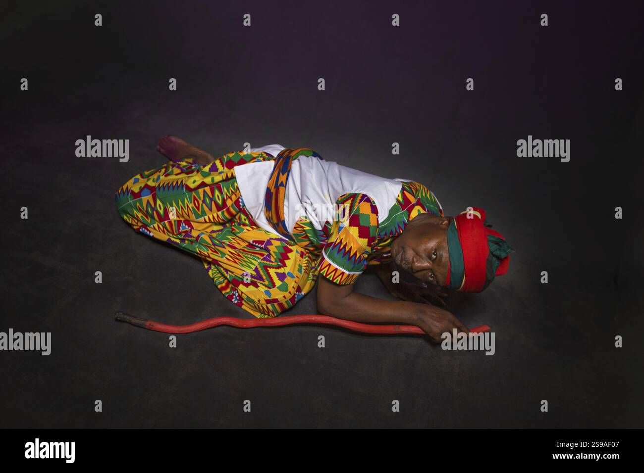 Afrikanischer Mann in traditioneller Kleidung, zahnloses Lächeln, auf grauem Hintergrund Stockfoto