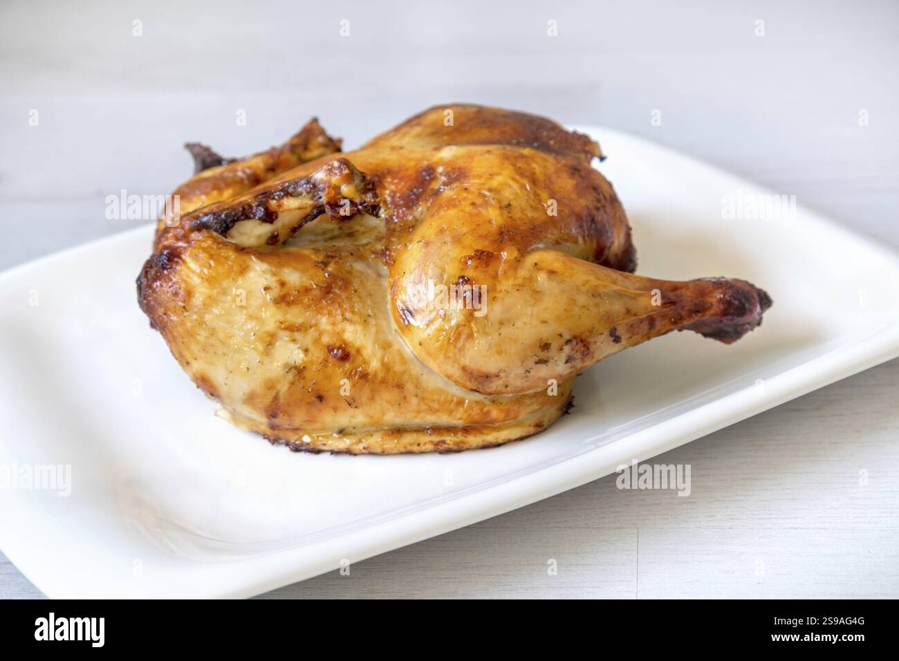 Ganzes goldgeröstetes Hühnchen auf weißem Hintergrund Stockfoto