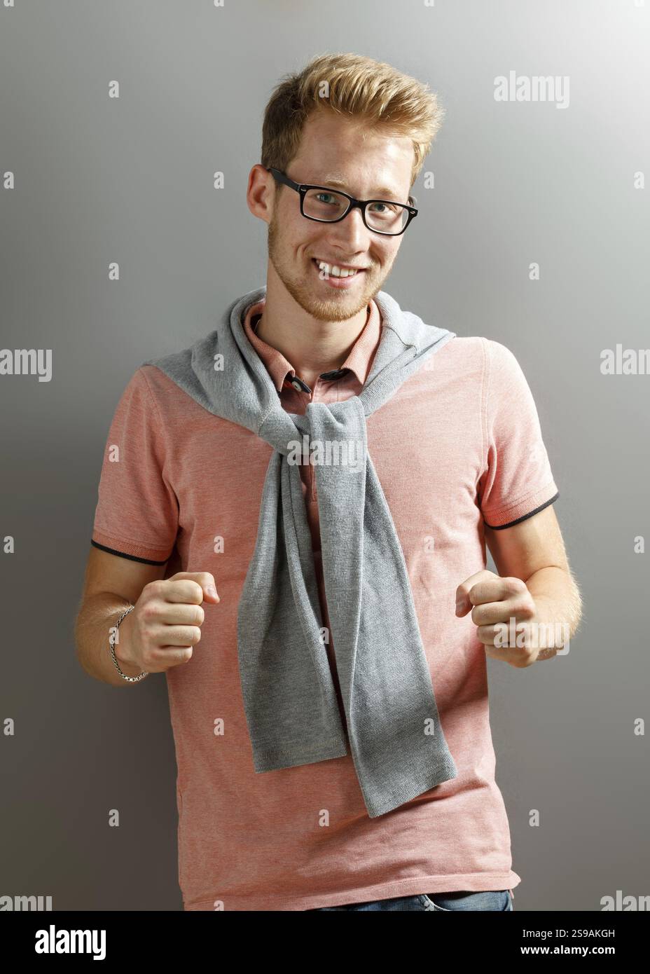 Hübscher junger blonder Mann auf grauem Hintergrund Stockfoto