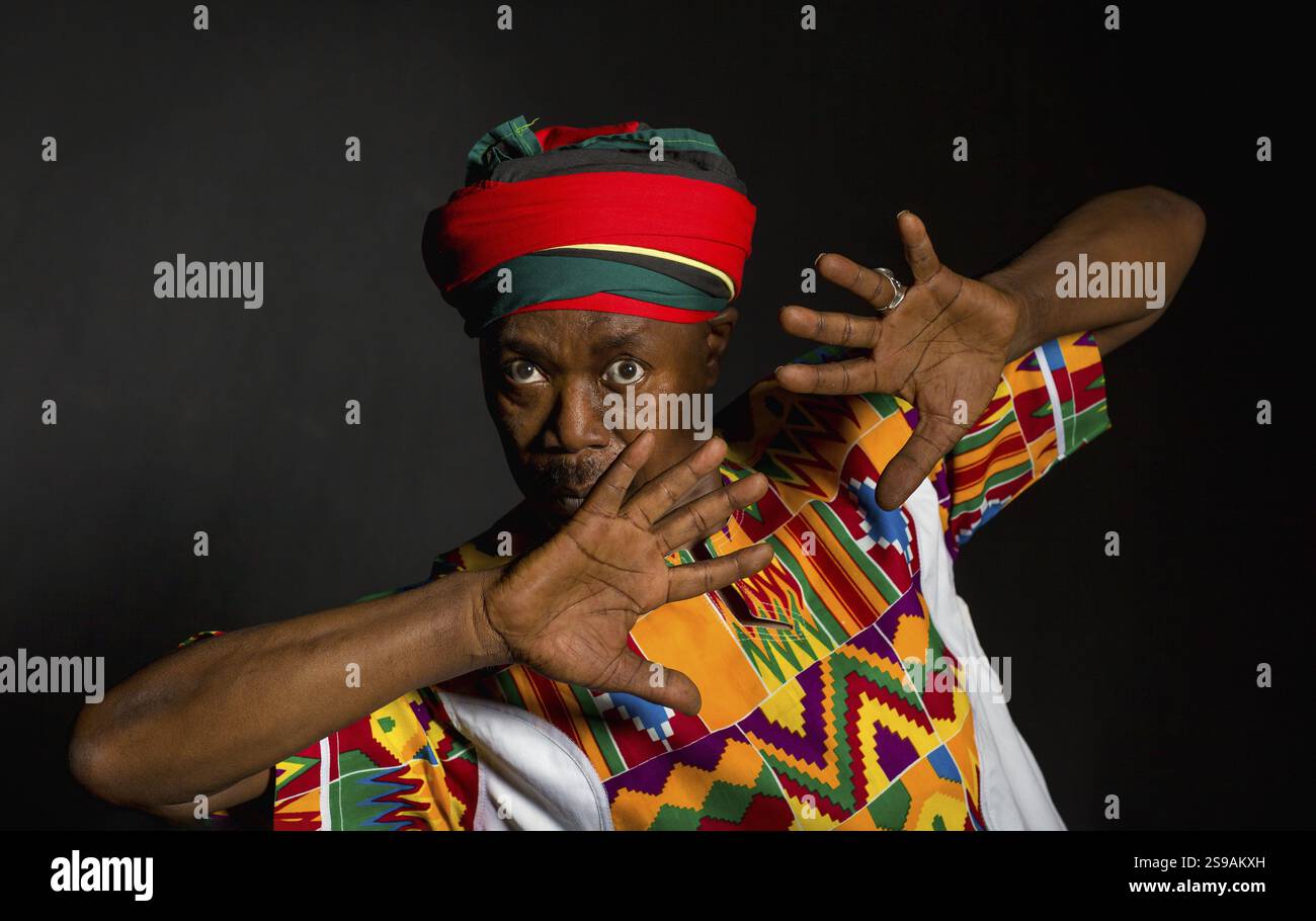 Afrikanischer Mann in traditioneller Kleidung, zahnloses Lächeln, auf grauem Hintergrund Stockfoto