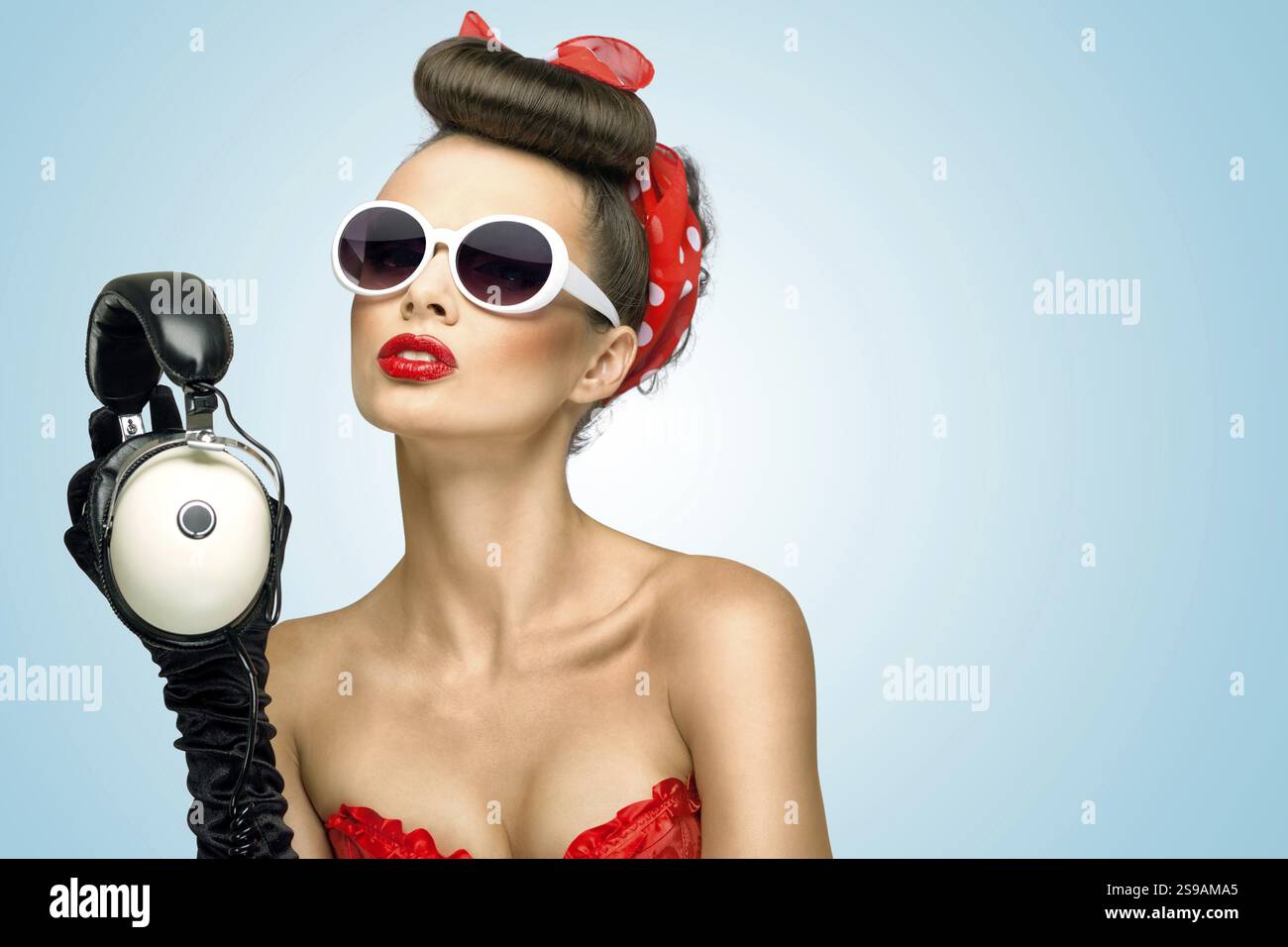 Retro-Foto eines niedlichen Pin-up-Mädchens mit Sonnenbrille und Vintage-Kopfhörern Stockfoto