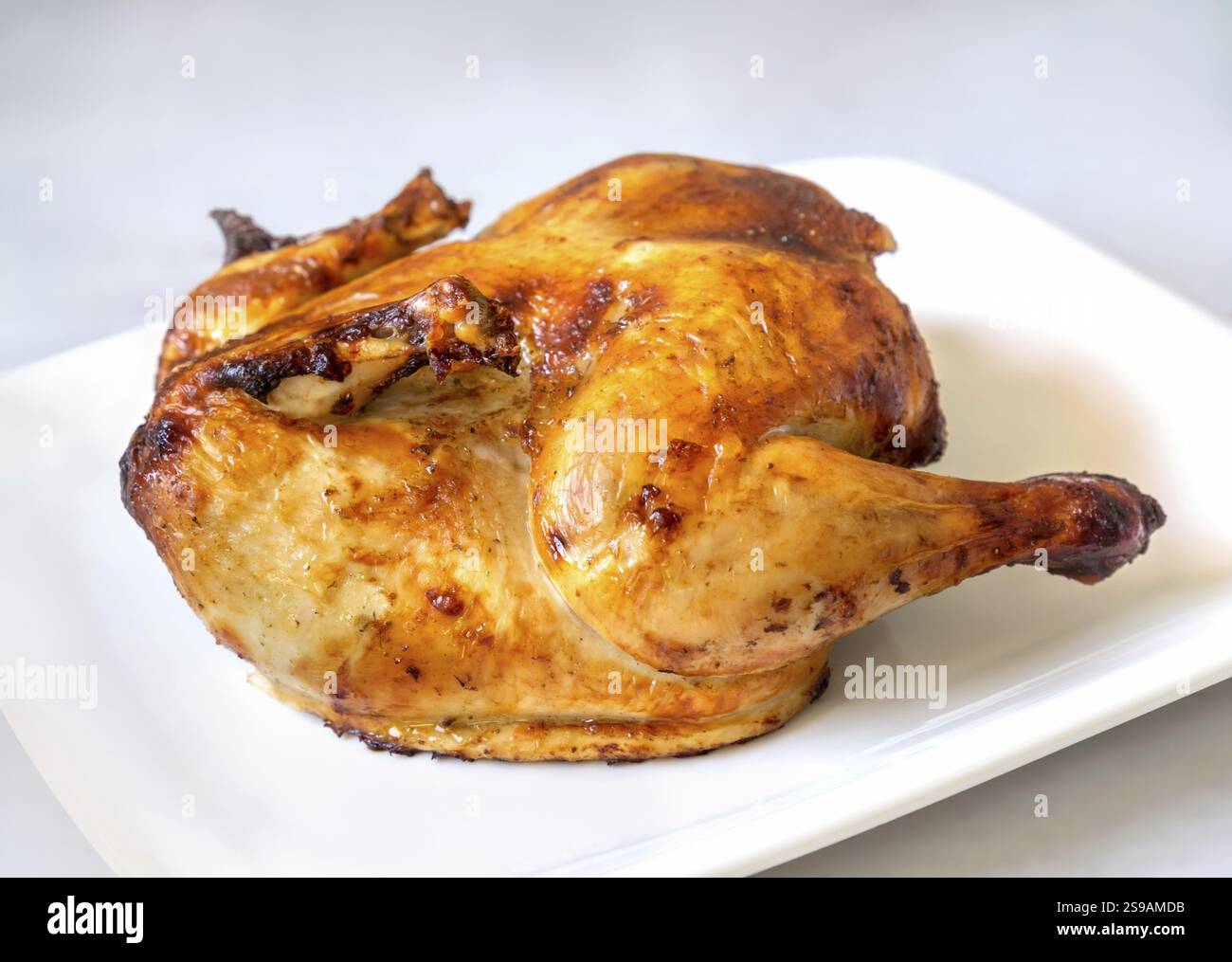 Ganzes goldgeröstetes Hühnchen auf weißem Hintergrund Stockfoto
