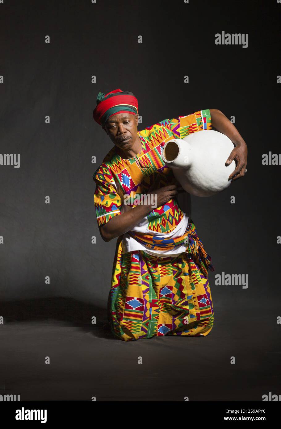 Afrikanischer Mann in traditioneller Kleidung, zahnloses Lächeln, auf grauem Hintergrund Stockfoto
