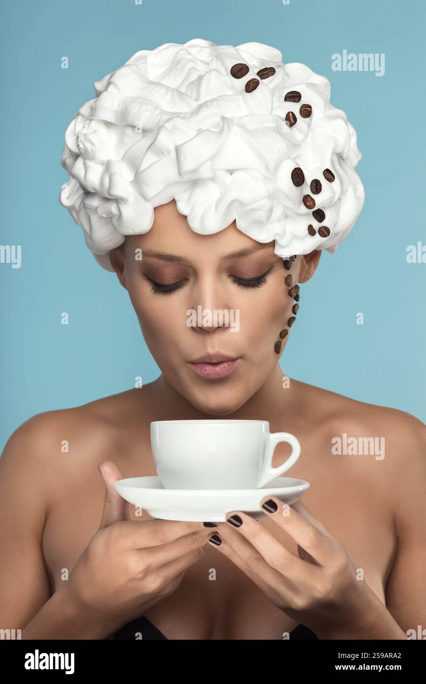 Eine junge Dame mit Schlagsahne auf dem Kopf und einer Kaffeetasse Stockfoto