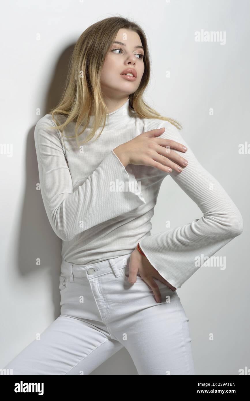 Porträt einer sexy schönen Frau mit langen blonden Haaren in weißen Kleidern, die im Studio mit weißem Hintergrund posiert, St. Petersburg, Russische Föderation Stockfoto