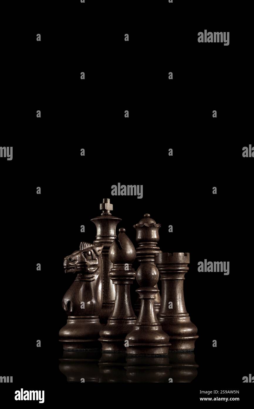 Strategie und Führungskonzept, schwarze Holzfiguren, die als Familie vor dunklem Hintergrund spielbereit stehen Stockfoto