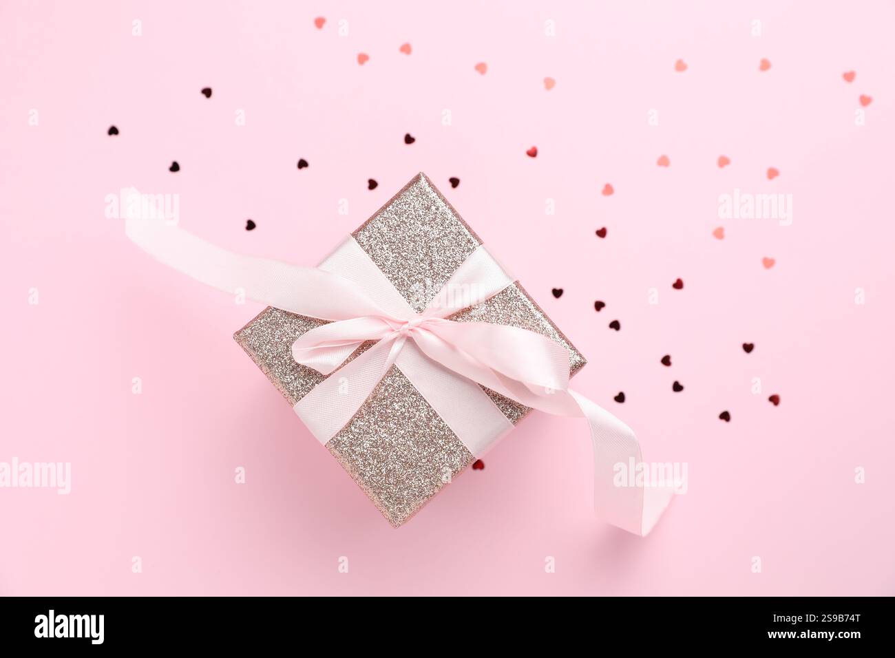 Romantisches Geschenk und Konfetti auf hellrosa Hintergrund, Draufsicht Stockfoto