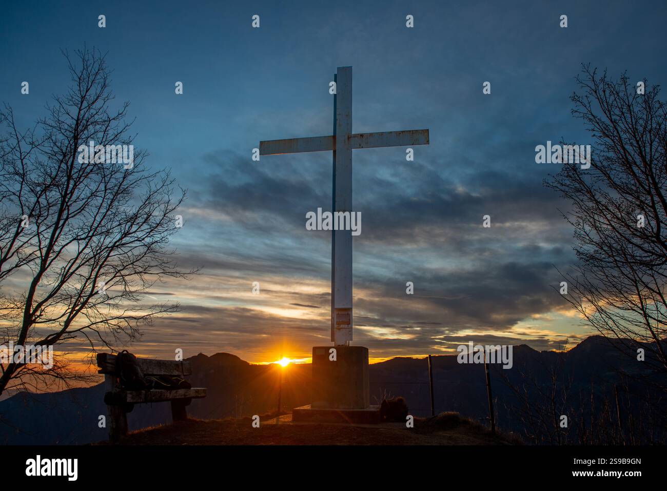 Eisenkreuz auf dem Berggipfel bei Sonnenuntergang Stockfoto