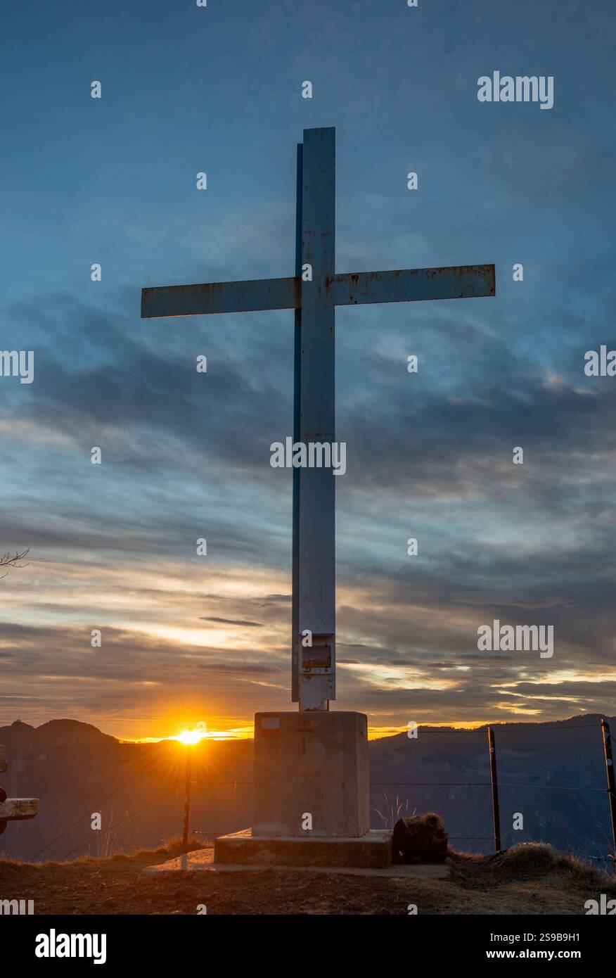 Eisenkreuz auf dem Berggipfel bei Sonnenuntergang Stockfoto