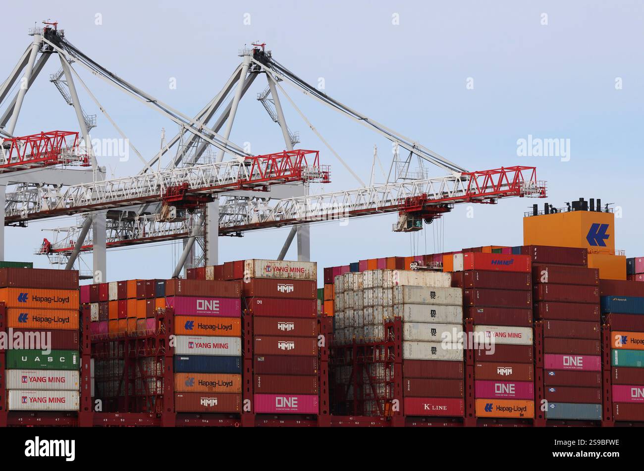 Eine Nahaufnahme des Daches eines großen Frachtschiffes, das in einem britischen Hafen angedockt ist und mit Frachtcontainern beladen wird, die von Kränen gestapelt werden Stockfoto