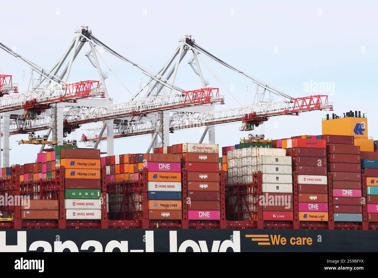 Eine Nahaufnahme des Daches eines großen Frachtschiffes, das in einem britischen Hafen angedockt ist und mit Frachtcontainern beladen wird, die von Kränen gestapelt werden Stockfoto