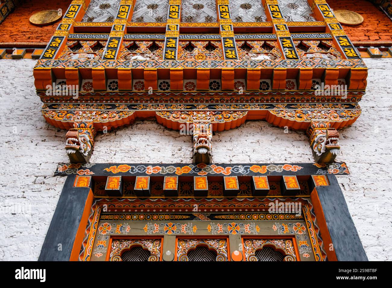 Orange, Schwarz und weiß sind die vorherrschenden Farben der wunderschön dekorierten Außenfassade in Punakha Dzong, Bhutan Stockfoto