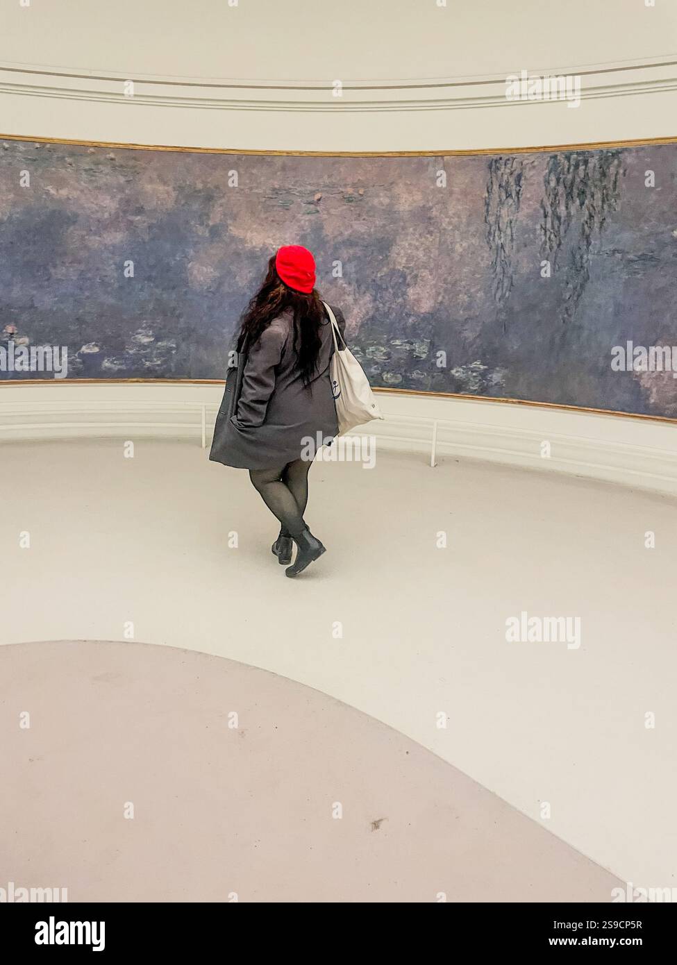 Eine junge Frau bewundert Monets Wasserlilien im Orangerie-Museum in Paris, eingetaucht in die Ruhe der impressionistischen Kunst. - Smartphone-aufgenommenes Stockfoto