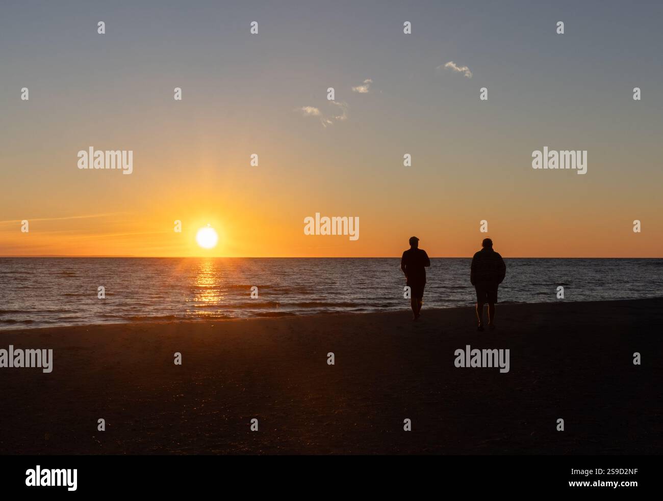 Zwei Männer beobachten den Sonnenuntergang in der Georgian Bay vom Strand in Ontario in der Nähe von Lafontaine Stockfoto