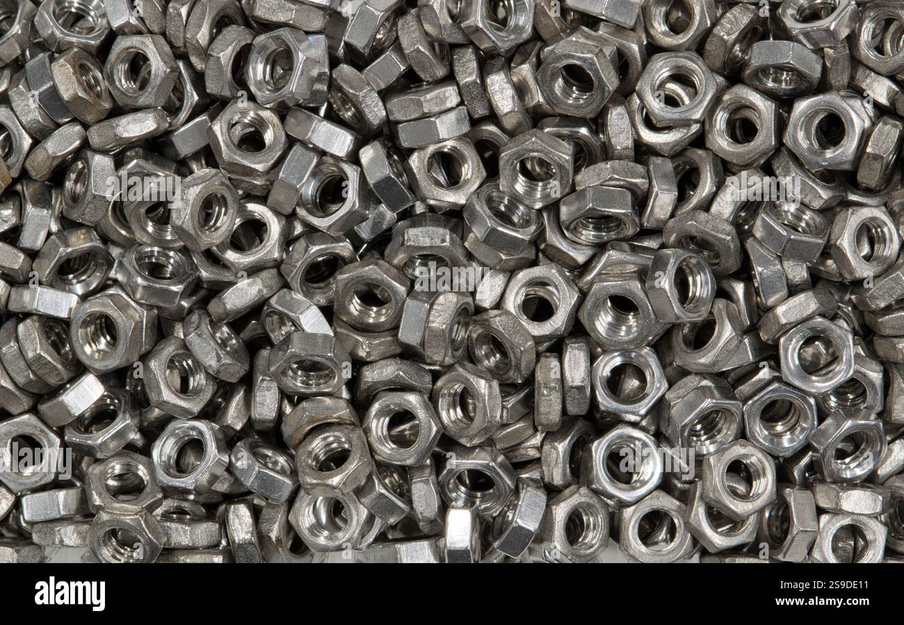 Metallmuttern lose verstreut mechanische Befestigungsteile Maschinenteile Arbeitsgeräte. Stockfoto