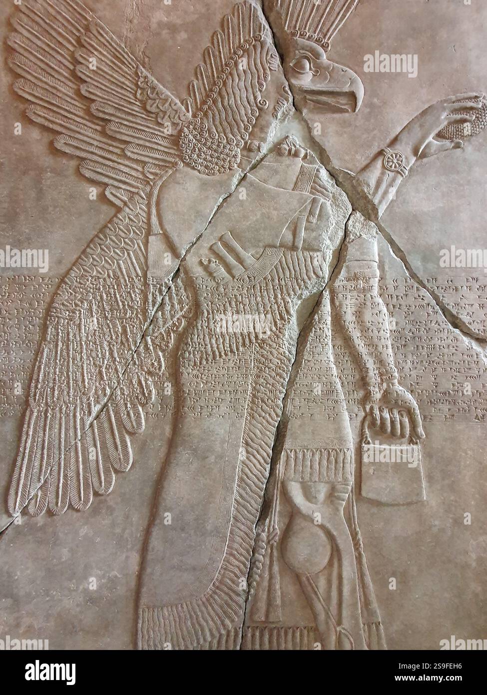 Vertikale Nahaufnahme eines Wandreliefs mit einem geflügelten mesopotamischen Adlergott, Apkallu oder Abgal, in einem alten assyrischen Tempel Stockfoto