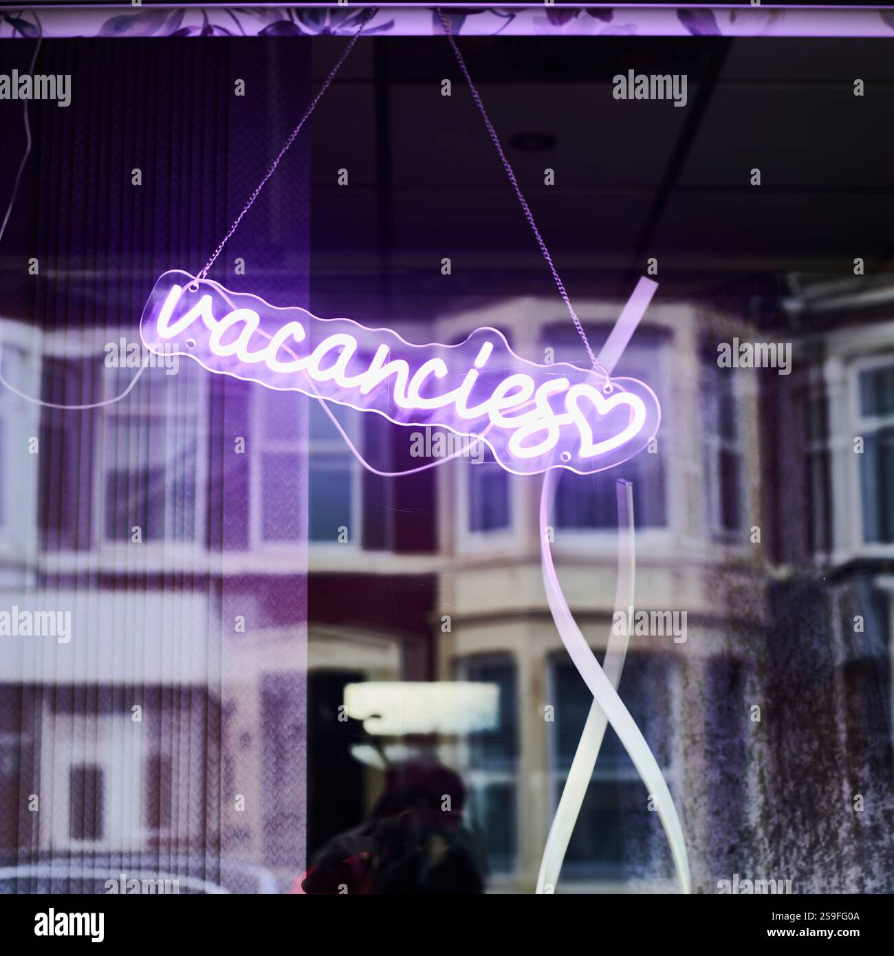 Violettes Neonschild im kleinen Hotelfenster Stockfoto