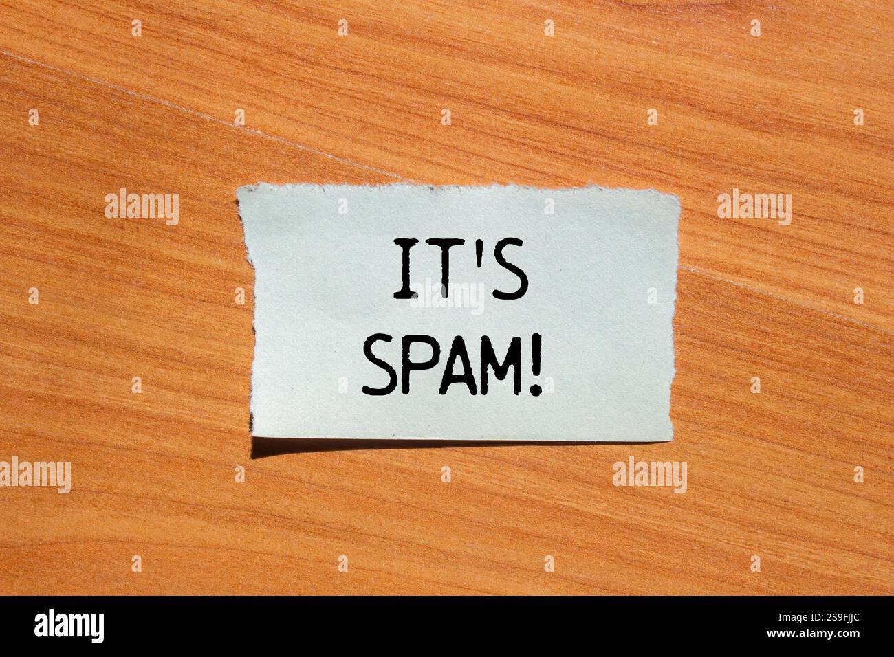 Es ist eine Spam-Nachricht, geschrieben auf zerrissenem Papierstück mit hölzernem Hintergrund. Konzeptionell ist das Spam-Symbol. Kopierbereich. Stockfoto