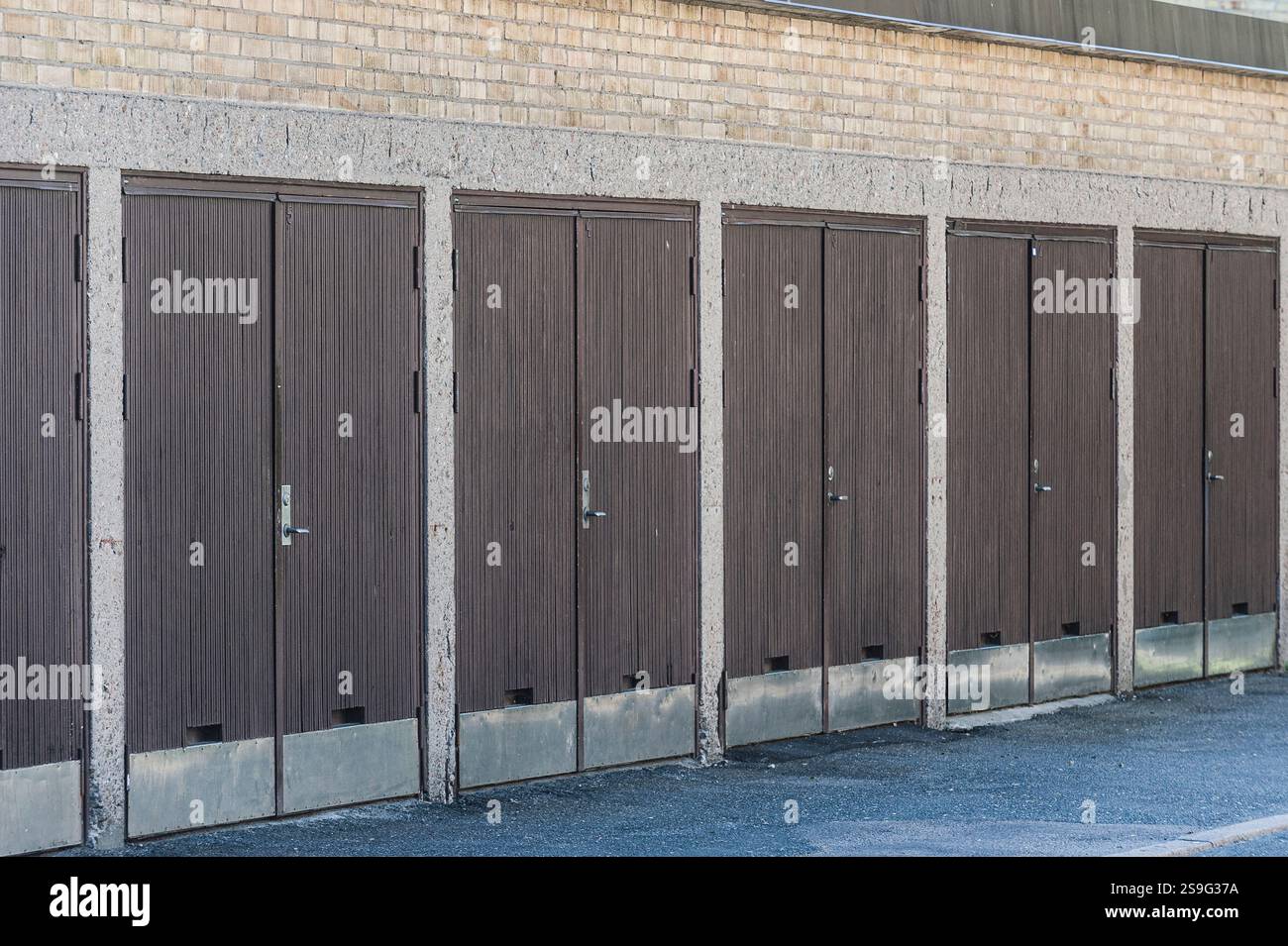 Mehrere Garagen stehen in einer ordentlichen Reihe, jede mit einer einfachen braunen Tür. Die klaren Linien und gedämpften Farben spiegeln einen minimalistischen Stil wider, der typisch für die Stadt ist Stockfoto