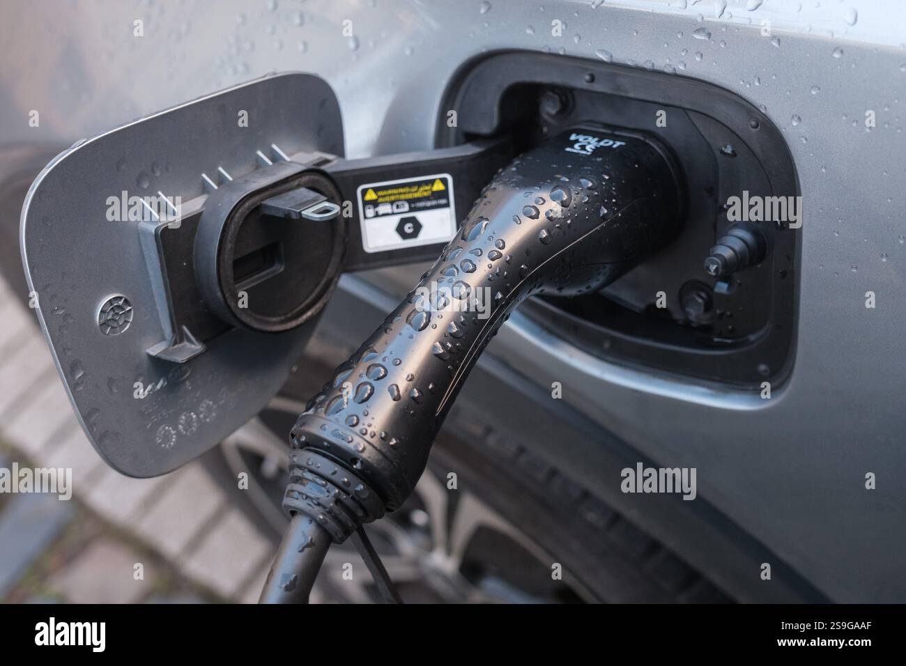 E-Auto wird geladen. Schließen Sie den Stecker während des Ladevorgangs an einem Elektroauto an. Stockfoto