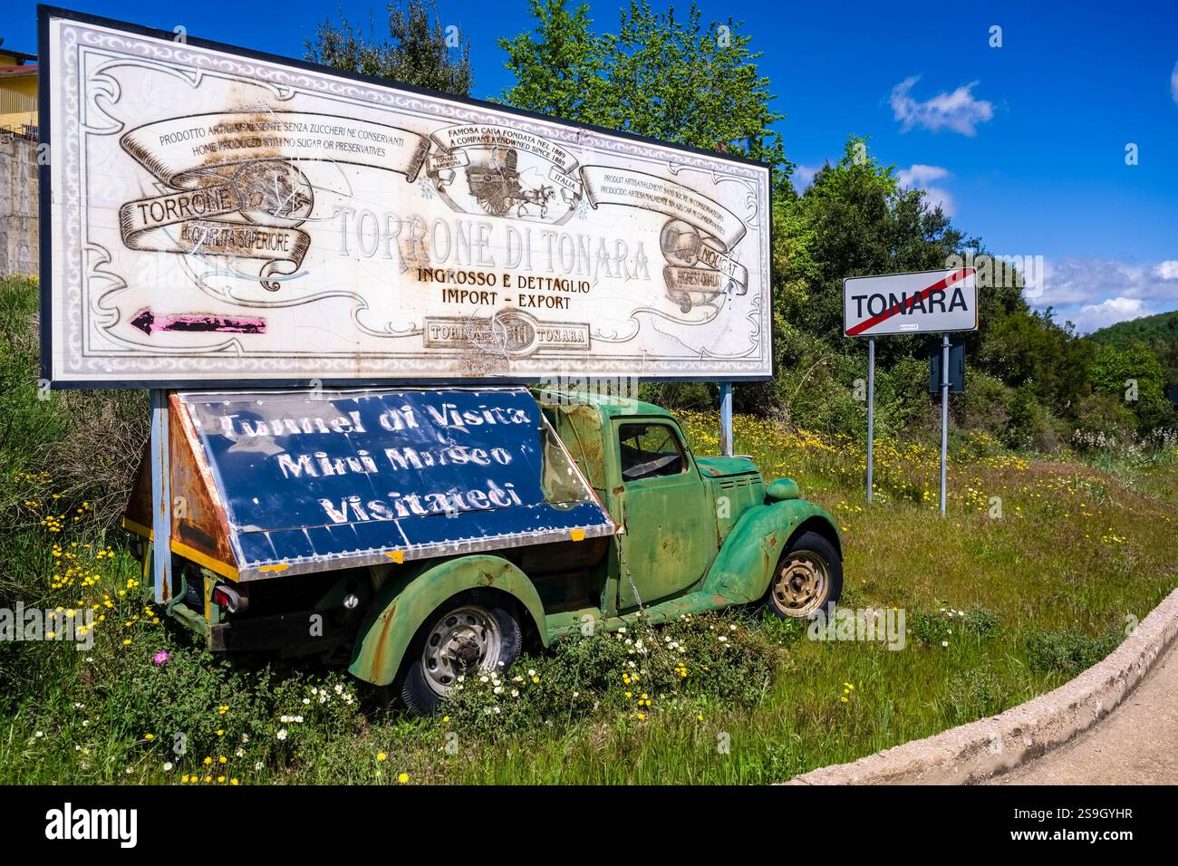 Große Werbetafel, montiert auf einem rostigen Vintage-Van am Eingang zur kleinen Stadt Tonara. Stockfoto