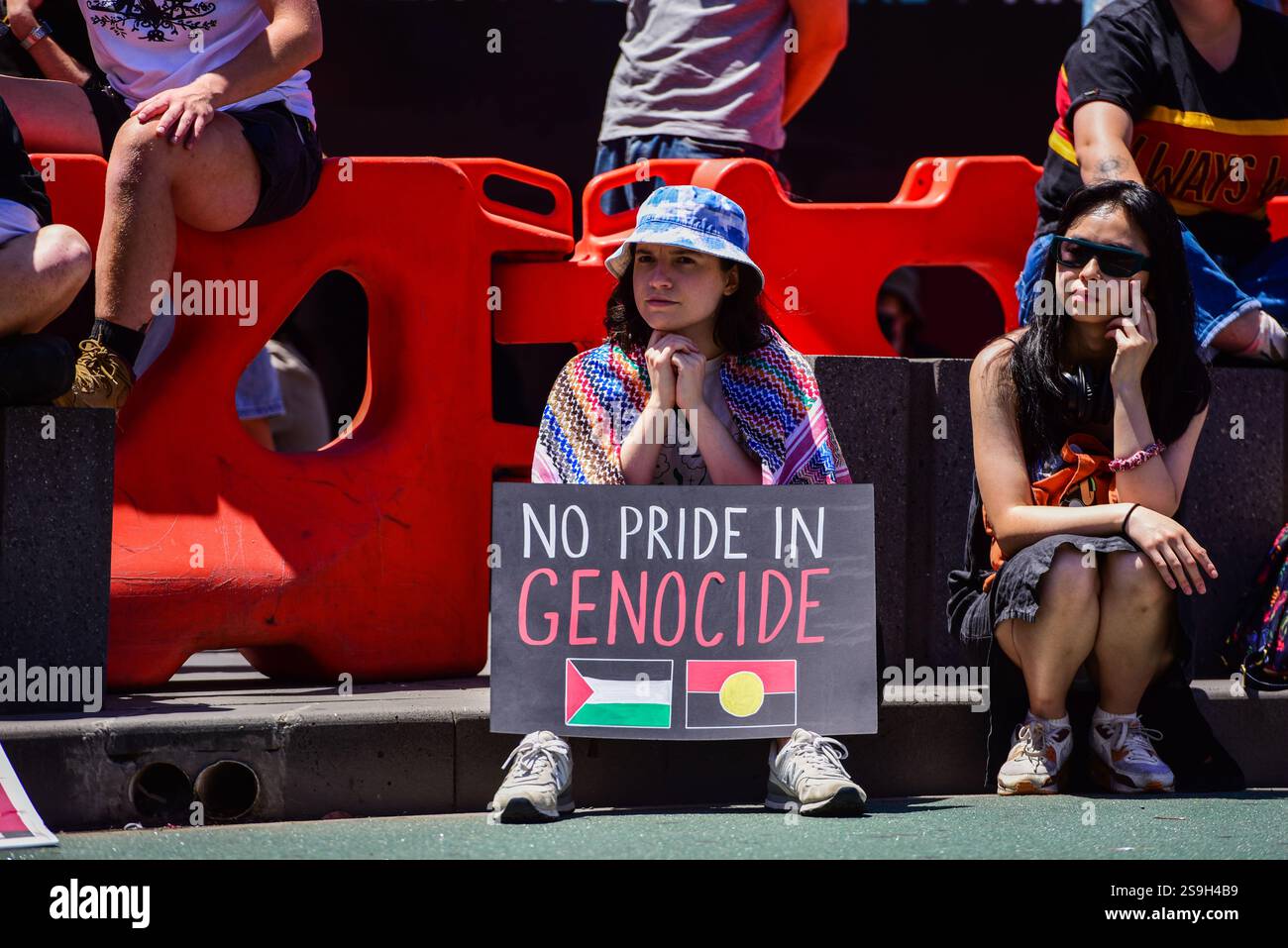 Ein Demonstrant hält ein Plakat mit der Aufschrift „kein Stolz auf Völkermord“, während er auf der Straße während der „Invasion Day“-Kundgebung gegen den Australia National Day zur Unterstützung der indigenen Australier sitzt. Die Kundgebungen zum „Invasionstag“ sind weit verbreitet: Am 26. Januar veranstalten die meisten Hauptstädte zahlreiche Proteste und Veranstaltungen, um die indigene Kultur an einem Tag zu feiern, der als Trauer für viele Menschen der First Nations betrachtet wird. Die Polizei von Victoria sagte, dass sie eine „sehr sichtbare Präsenz“ im gesamten CBD von Melbourne hatten, wo 25.000 vom Parlamentsgebäude zur Flinders Street marschierten und gegen 16:00 Uhr endeten. Stockfoto