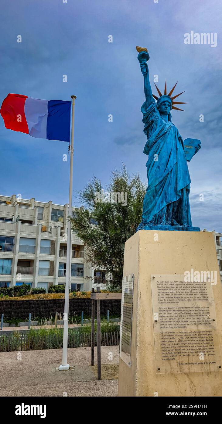 Die Freiheitsstatue, die Freiheit, die die Welt erleuchtet, in der Nähe der französischen Flagge, die im Wind fliegt. 30. Juni 2023. Soulac-sur-Mer, Nouvelle-Aquitaine Stockfoto