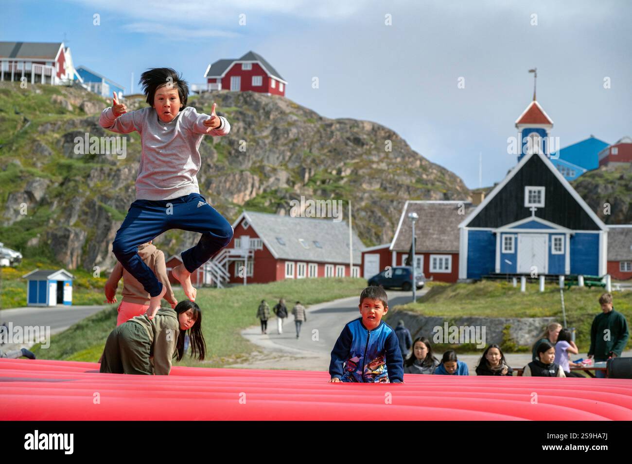 Kinder in Sisimiut, Grönland, genießen einen Sommertag, der auf einem Trampolin springt und die lebendige Kultur und den verspielten Geist der Inuit-Gemeinschaft verkörpert. Stockfoto