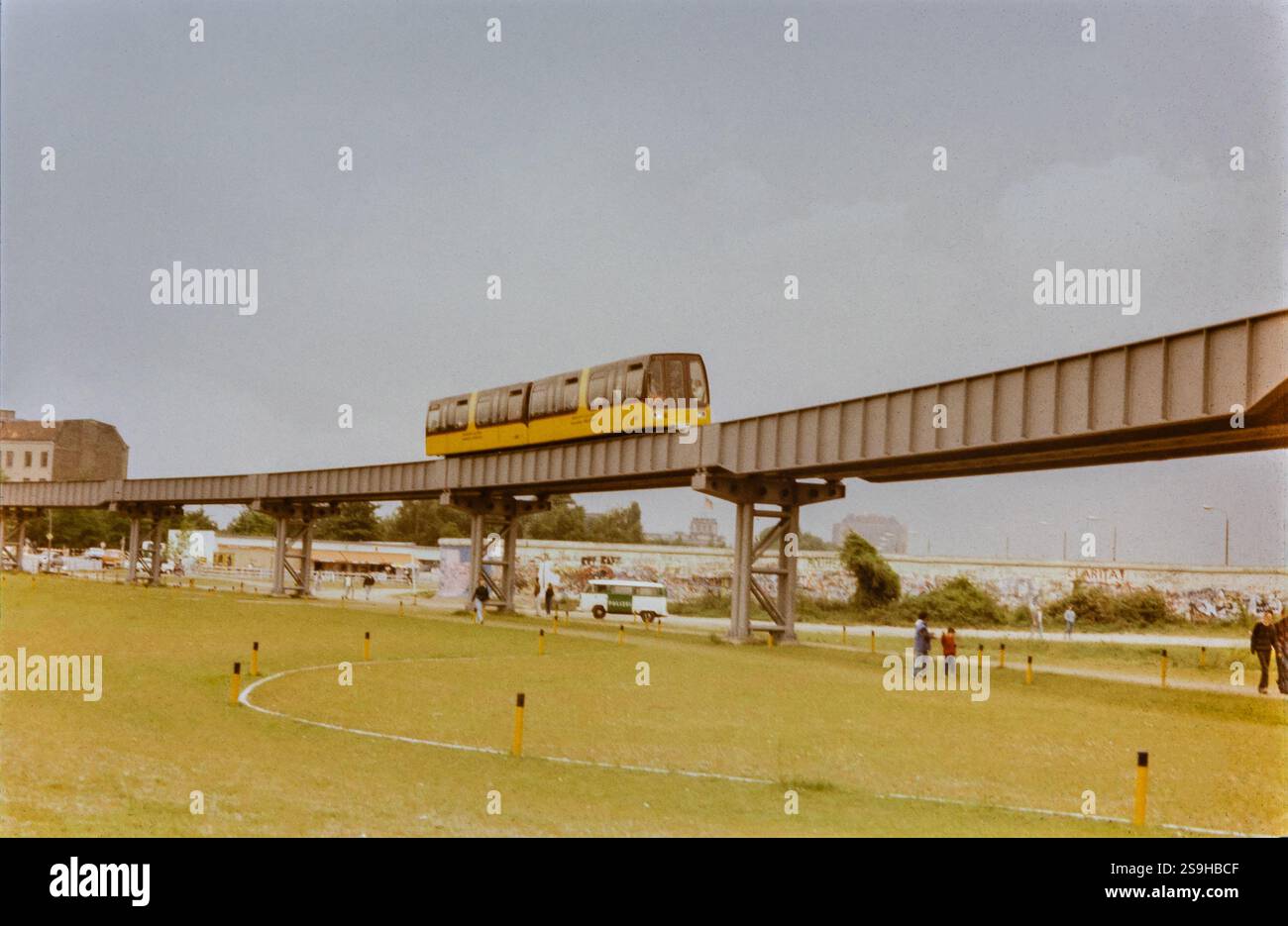 Berlin, Deutschland. September 1990. Eine gelbe M-Bahn (Magnetbahn oder Maglev-Zug), die hier über den Tilla Derieux-Park im Berliner Stadtteil Tiergarten zwischen den Stationen Kemper Platz und Bernburger Straße verläuft. Im Hintergrund sind Reste der Berliner Mauer sichtbar. Die Berliner M-Bahn bediente das öffentliche Verkehrsnetz vom 28. August 1989 bis zur Stilllegung am 17. September 1991. Stockfoto