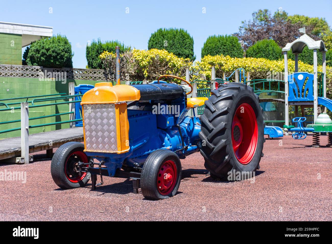 Blau, orange und rot lackierter Traktor auf einem Kinderspielplatz in Neuseeland Stockfoto