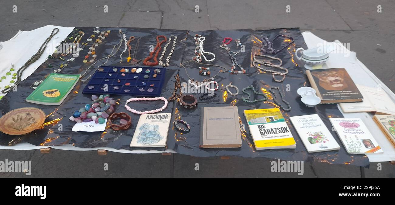 Europäischer Antiquitätenmarkt, Stand am Flohmarkt : farbenfrohe Kristallsteine, Kristallschmuck, Bernsteinketten, Vintage-Spielzeug, Vintage-Bücher, Vintage Rosenkranzperlen, Naturstein- und Mineralhalsketten, Edelsteinanhänger, Vintage Medaillen, Vintage Lederbrieftaschen, Vintage Gusseisenschere, Vintage Lederhandschuhe, Vintage Modeschmuck, Vintage Kreuz Stockfoto