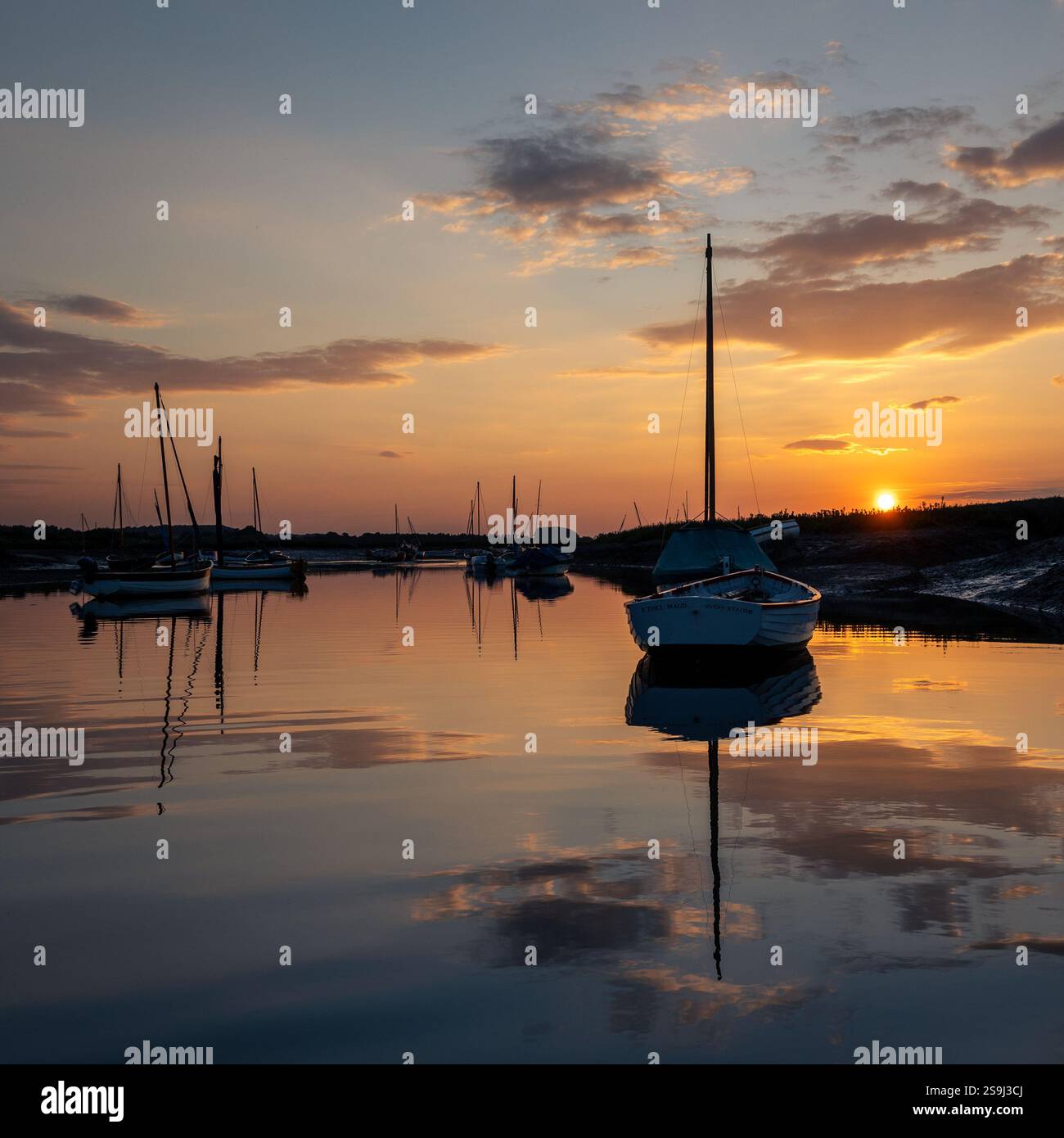 Sonnenuntergang spiegelt sich im ruhigen Wasser von Burnham Overy Staithe Stockfoto