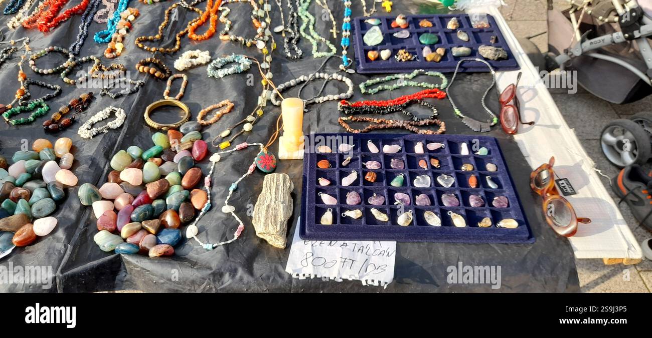 Europäischer Antiquitätenmarkt, Stand am Flohmarkt : farbenfrohe Kristallsteine, Kristallschmuck, Bernsteinketten, Vintage-Spielzeug, Vintage-Bücher, Vintage Rosenkranzperlen , Naturstein und Mineralkette, Edelstein Anhänger, Vintage Lederhandschuhe, Vintage Modeschmuck, Vintage Stein ( Mineralsteine Halbedelsteine ) Kreuz, Messing Armbänder, Kristallarmbänder, Fossilien, Achat, bescheidene Steine aus Rosenquarz, Vintage-Schweinespielzeug, Vintage-T-rex-Spielzeug, massive handgeschnitzte Holzschildkröte / Schildkrötenkopf Stockfoto
