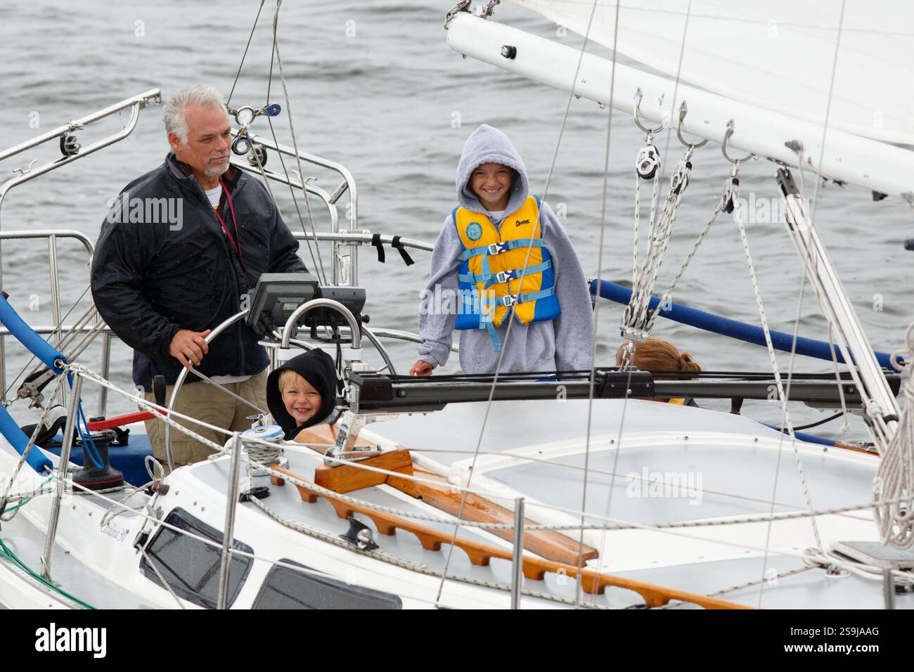 Ein Mann mit Kindern segelt sein Boot während des Tall Ships Festivals in den Hafen von Duluth. Stockfoto