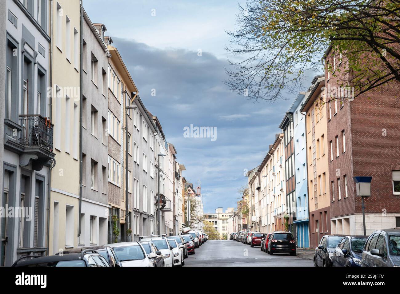 Vorstadtstraße in Aachen gesäumt von mehrstöckigen Wohnhäusern. Geparkte Autos und einheitliche Fassaden bilden ein typisches westeuropäisches Viertel Stockfoto