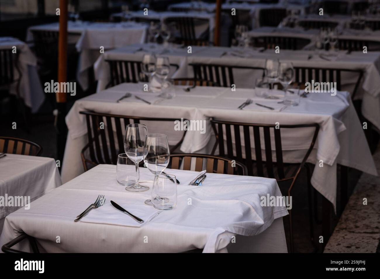 In einem italienischen Open-Air-Restaurant im Zentrum Roms stehen ordentlich gedeckte Tische mit weißer Bettwäsche bereit. Gläser und Besteck erwarten Gäste, die es genießen möchten Stockfoto
