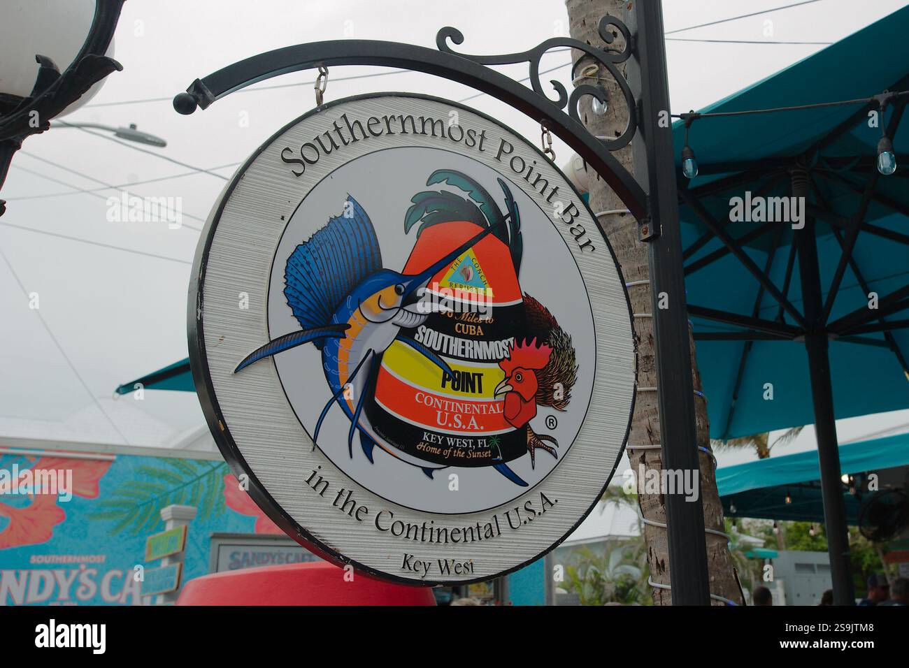 Nur zur redaktionellen Verwendung am 20. Januar 2025, Key West, Florida, USA. Kreiszeichen für südlichste Punktleiste. Farbenfroher Papagei hängt an Metallpfosten. In der Nähe von K Stockfoto