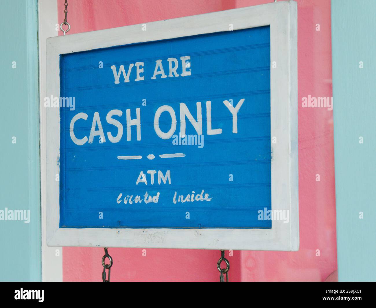 Blaues und weißes Schild mit den Worten We are Cash Only an einer pinkfarbenen Wand. Geldautomat-Innenkopie unten. Stockfoto