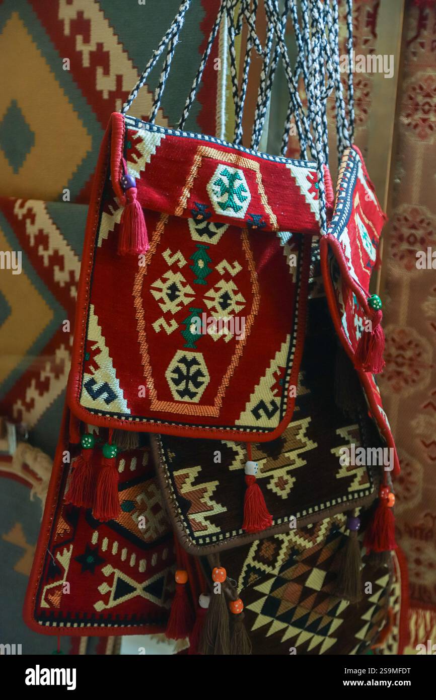 Farbenfrohe Taschen mit komplizierten Mustern und Texturen sind wunderschön angeordnet und zeigen traditionelle albanische Handwerkskunst in einem Marktumfeld Stockfoto