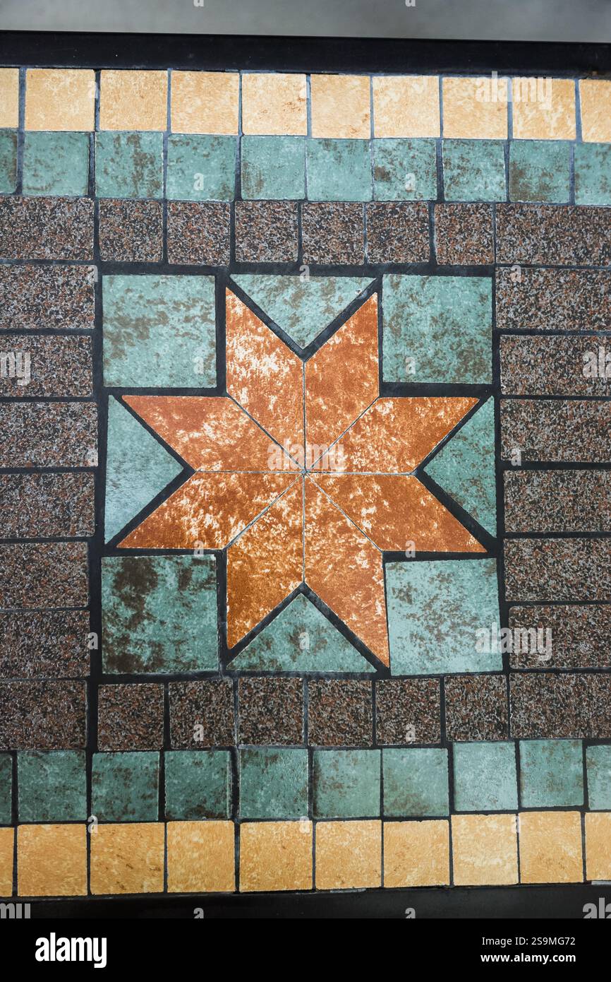 Das faszinierende Mosaikdesign zeigt ein Sternmuster, das in Erdtönen und kräftigen Farben gestaltet wurde und die komplizierte Handwerkskunst auf den Fliesen unterstreicht Stockfoto
