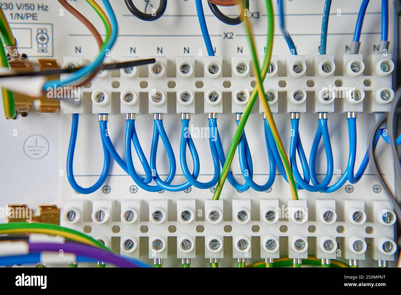 Farbenfrohe Drähte und Komponenten, die mit dem Anschlussblock im Verteilerkasten verbunden sind. Elektrische Leiterplatte mit Verkabelung und Anschlüssen Stockfoto