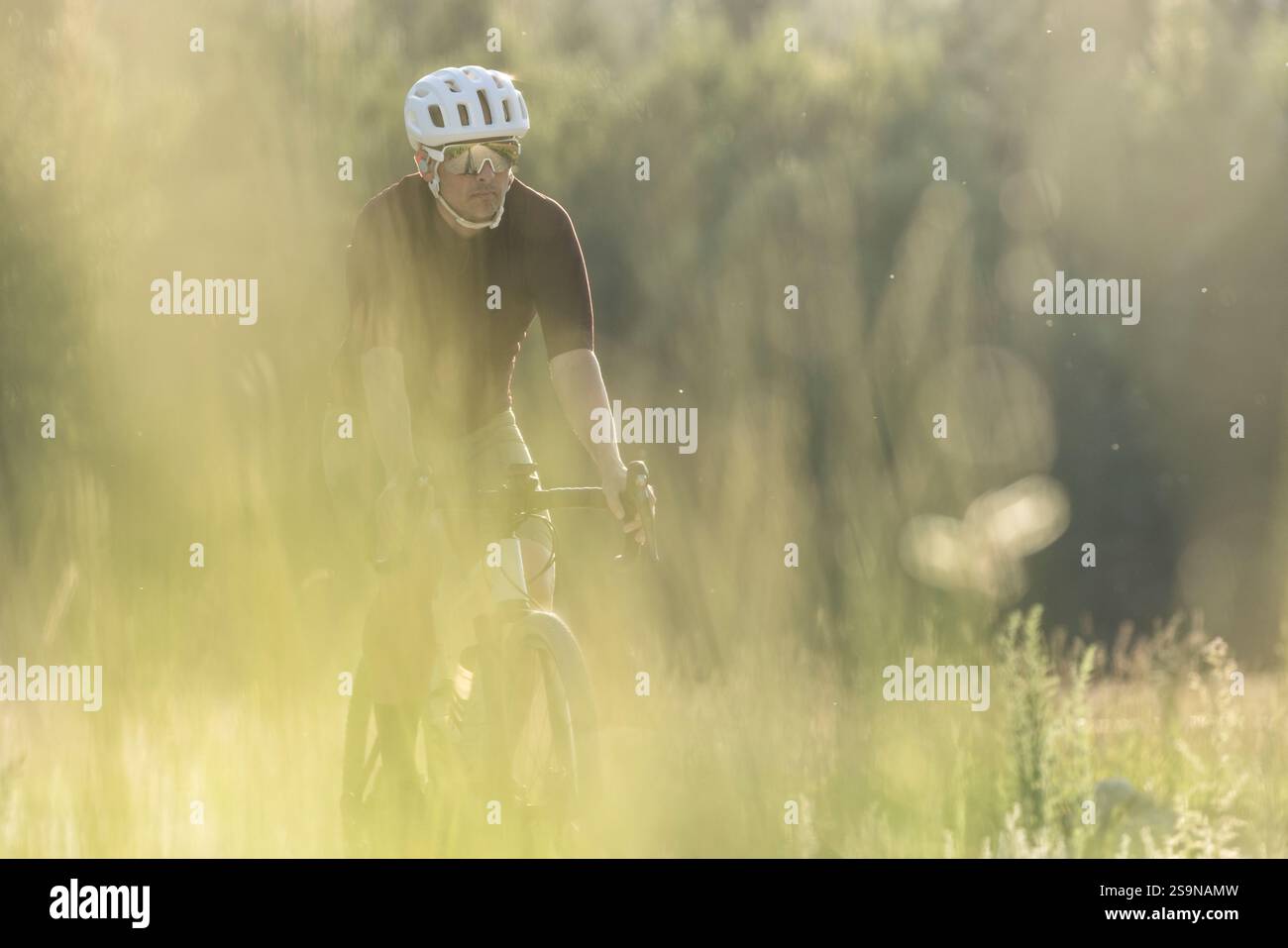 Schotterbiker auf einem unbefestigten Weg während der goldenen Stunde in einem ruhigen Tal Stockfoto