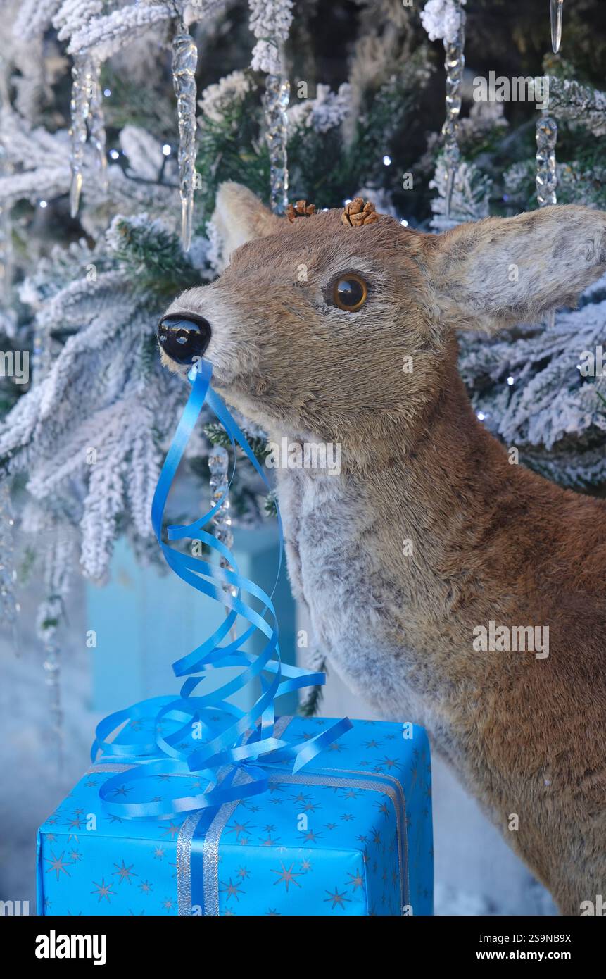 Künstliches Hirsch mit blauem Band auf weihnachtsgeschenk im Schaufenster Stockfoto