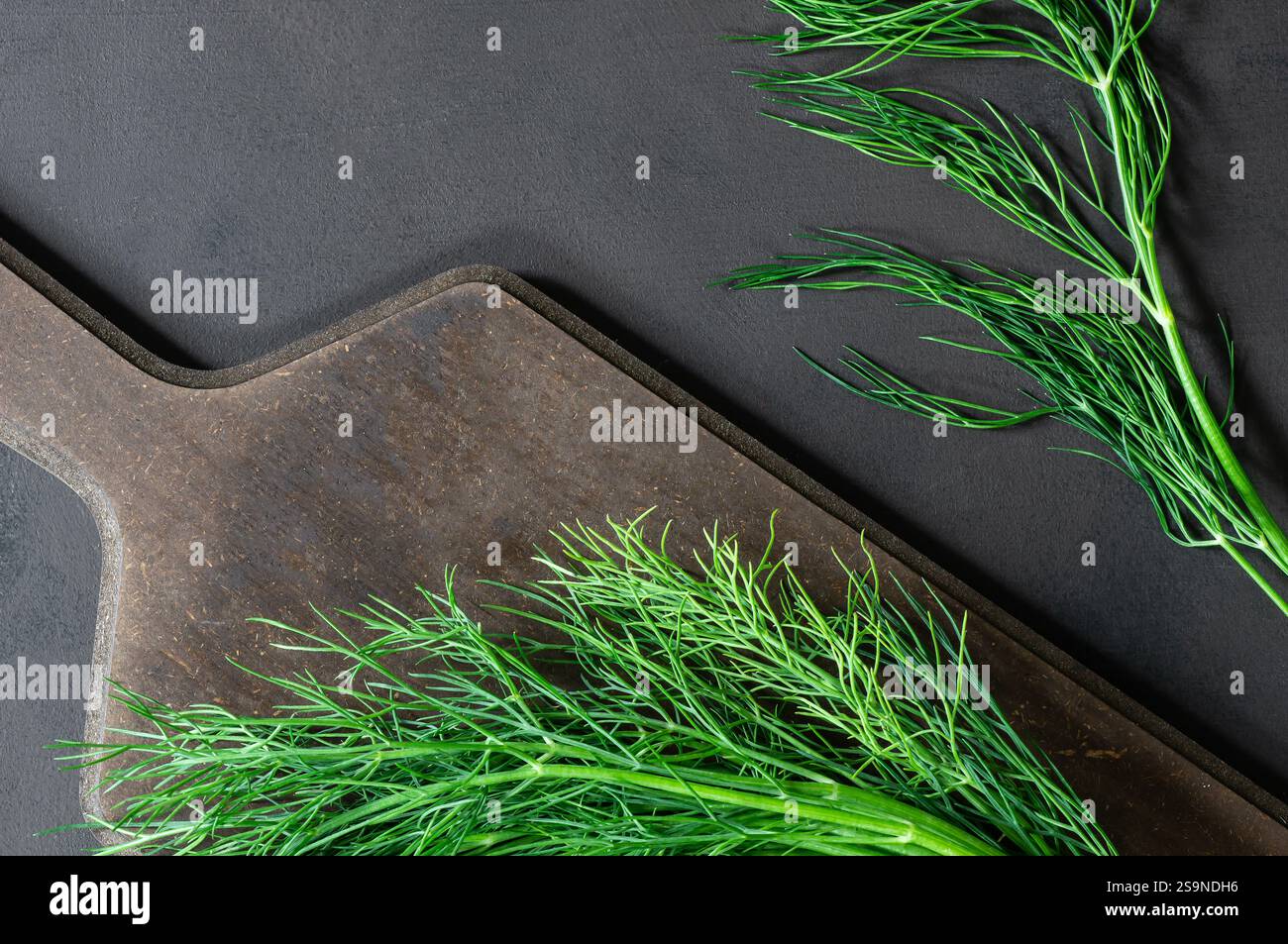 Bund frischer grüner Dill mit Schneidebrett auf rustikalem Tisch, grünes Blattgemüse, gesundes Essen, (Anethum graveolens) Stockfoto